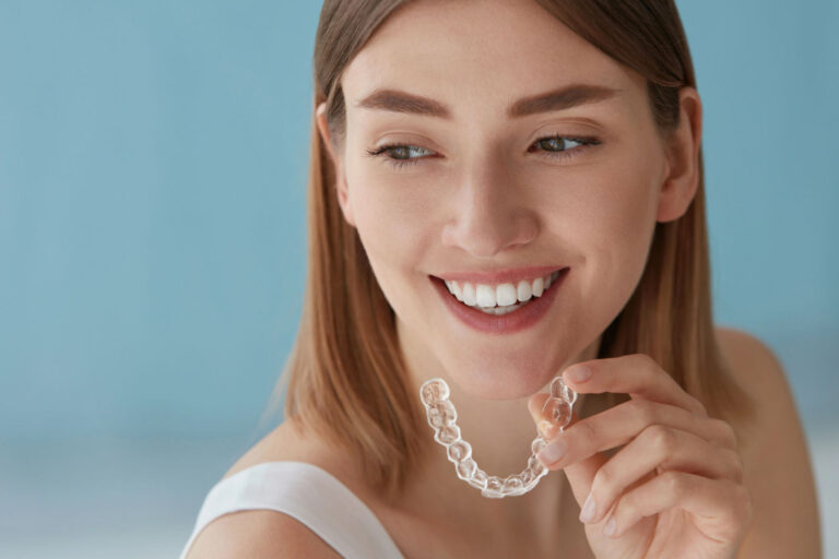 Junge, braunhaarige Frau mit Zahnschiene in der Hand, blauer Hintergrund