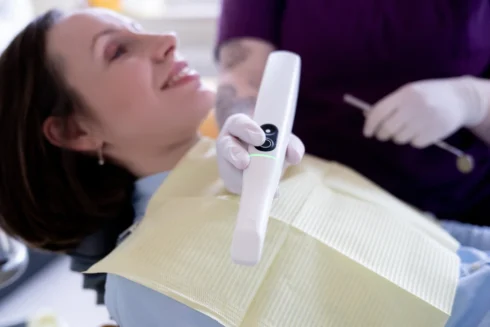 Close up Intraoralscanner auf einer Patientin mit gelbem Patientenlätzchen