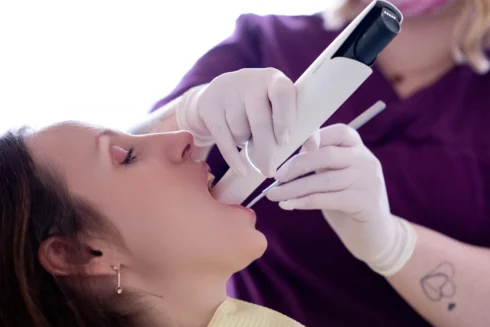 Close up Intraoralscanner wird von einer ZFA in den Mund einer Patientin gehalten