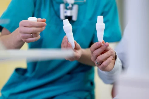 Close up Dimitri Tanurcov hält Modelle von Implantats-Schrauben